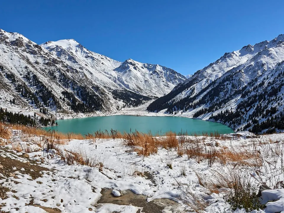 Big Almaty Lake below snowy peaks in early autumn, in the mountains above the city