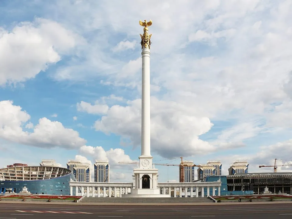 The tall white Kazakh Eli Monument on a square under a cloudy sky