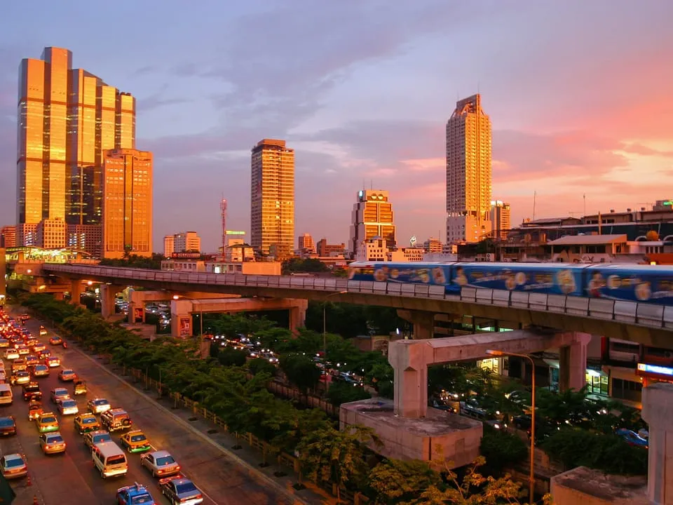 The Skytrain and the modern skyline above a busy road at sunset