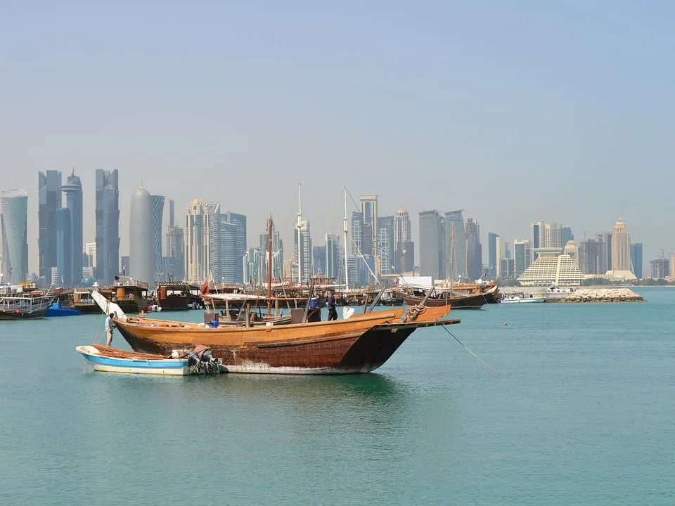 A wooden dhow in Doha Bay, with the towers of West Bay behind