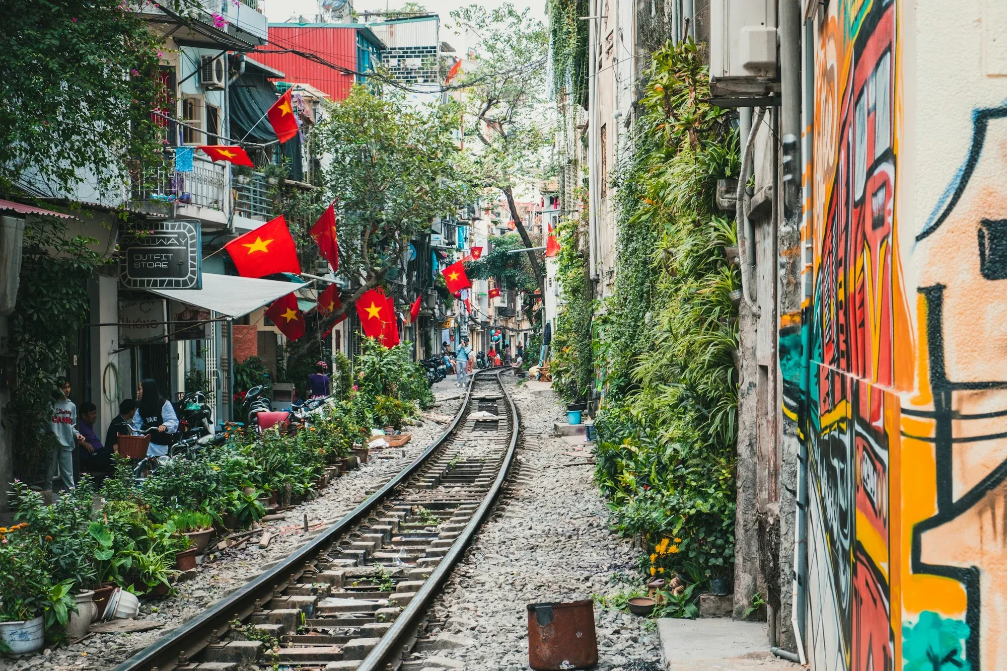 Hanoi's Train Street, with a railway running between houses, potted plants and Vietnamese flags
