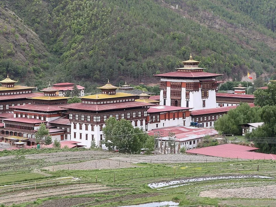 Tashichho Dzong, a white fortress-monastery below forested hills